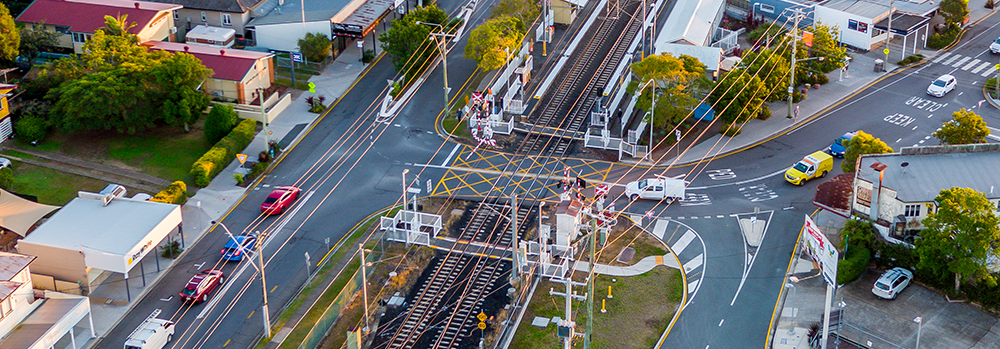 Aerial image of rail crossing, cars on either side of the crossing waiting to cross. 