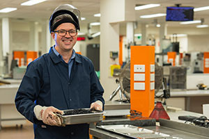 Person holding a tray of bitumen, standing in a labratory. 