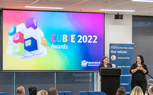 Director-General Sally Stannard standing at a podium with a female auslan interpreter.