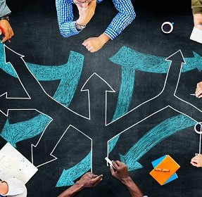 Image of people sitting at a table with arrows pointing in different directions on it.