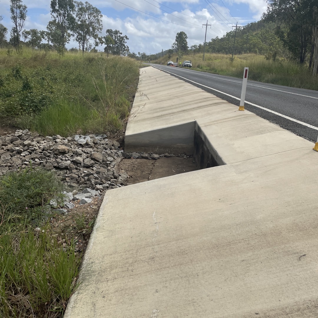 Concreate slab on the side of a road with a drainage to help prevent flooding.
