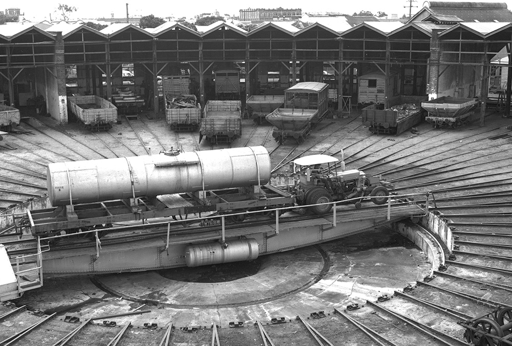 Historical photo of the Roundhouse turntable in use with multiple freight wagons picture in the background”