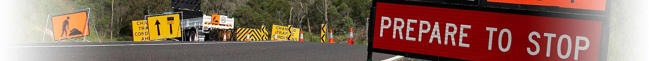 A sign that says "prepare to stop", on one side of the road and the other side there are other construction signs and a truck.
