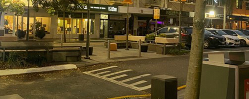 A street in Woolloongabba with trees, buildings and parked cars.