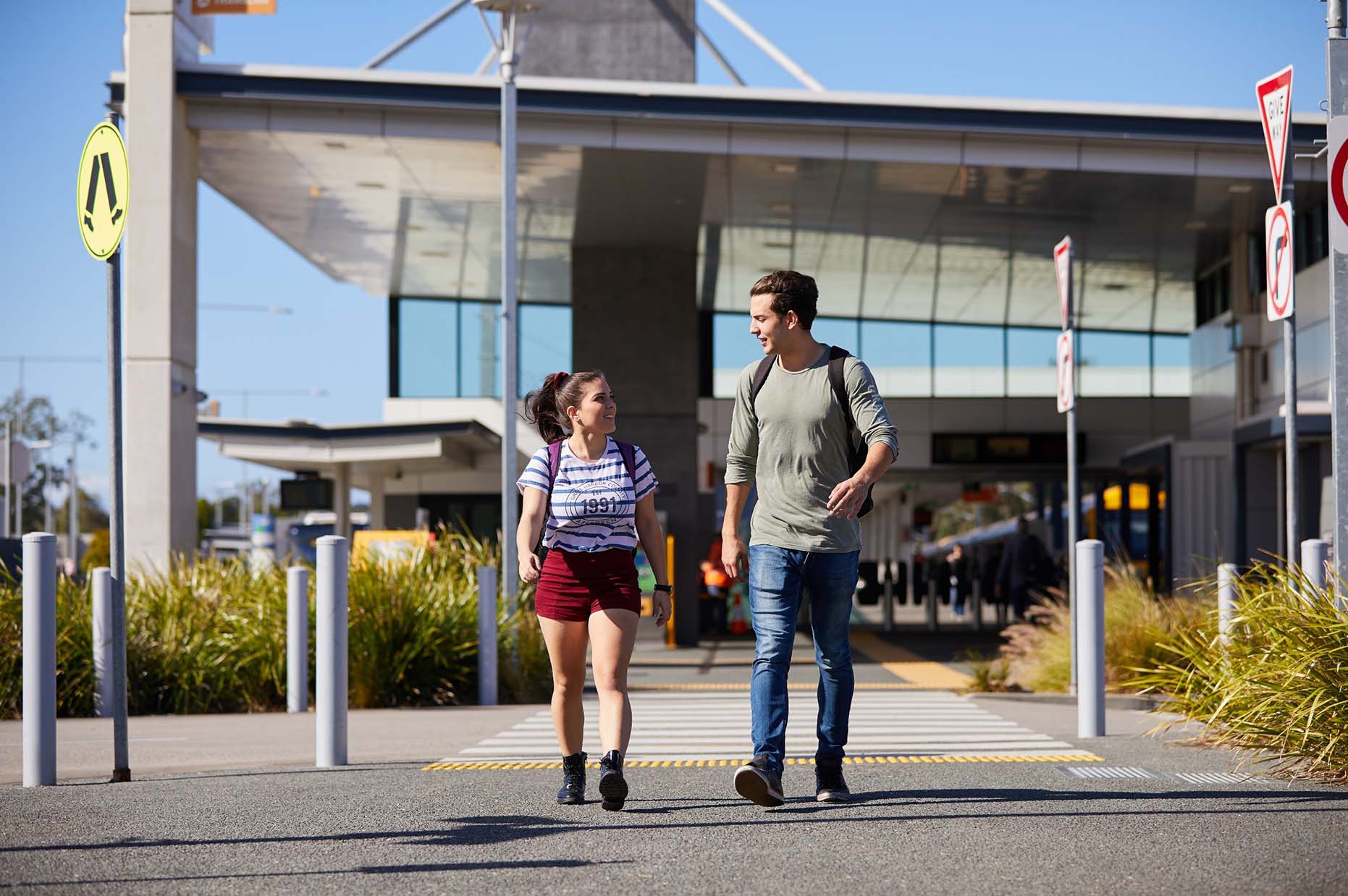 2 people walking, train station in the background