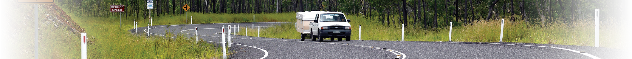 A car with a caravan driving down a winding road.